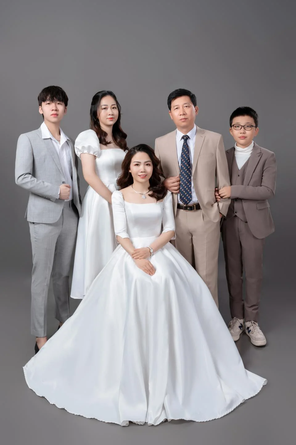 Ảnh gia đình mặc trang phục trang trọng với cô dâu ngồi phía trước