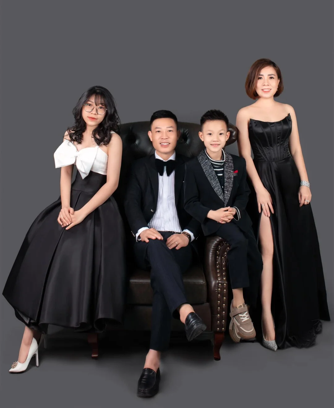 Ảnh gia đình bốn người tạo dáng trang trọng trong studio