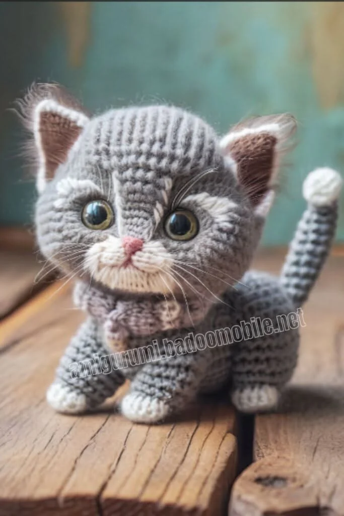 Mèo con len móc màu xám ngồi trên sàn gỗ