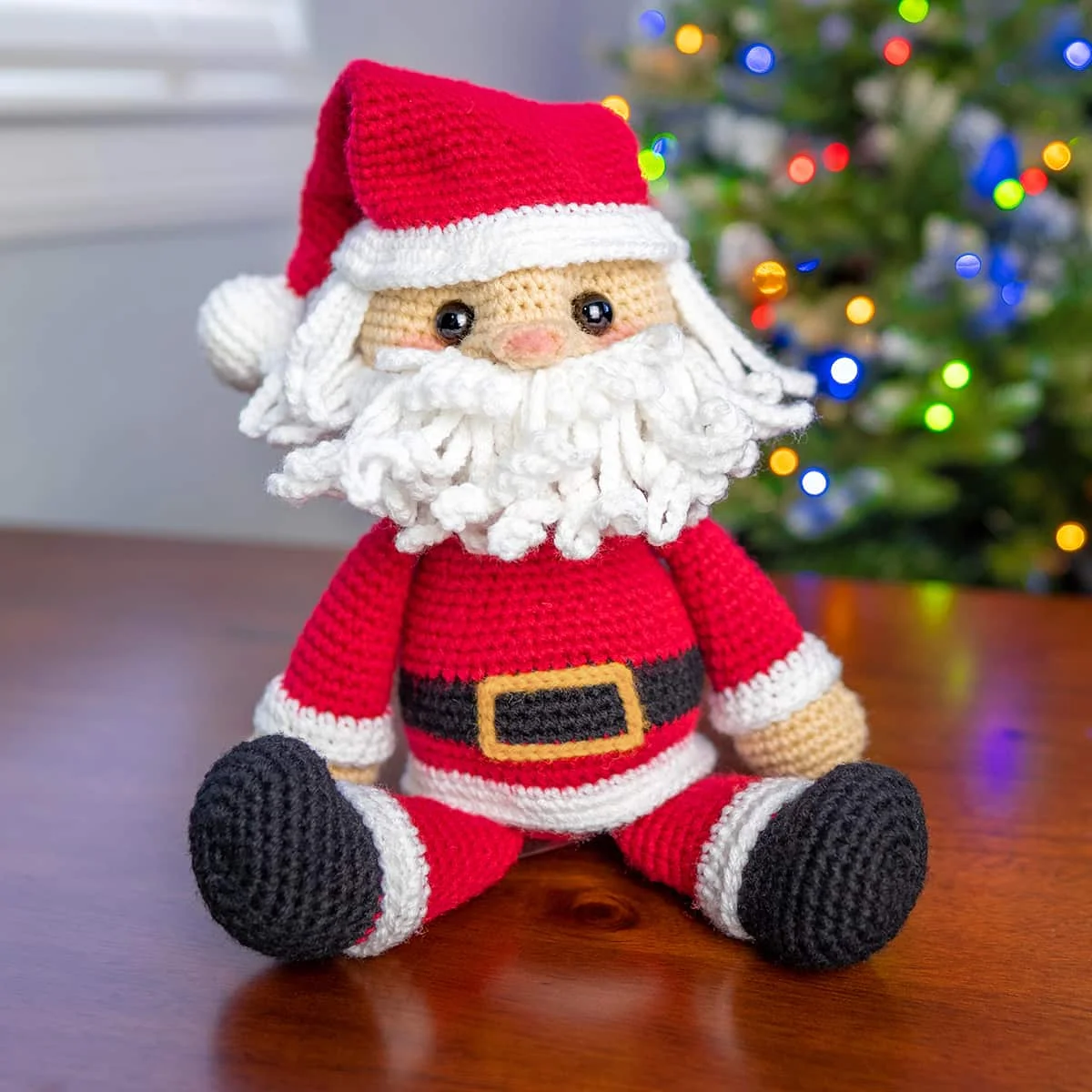 Ông già Noel len móc ngồi cạnh cây thông Giáng sinh